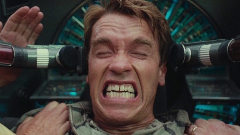 Arnold Schwarzenegger în rolul lui Douglas Quaid care se strâmbă sălbatic în Total Recall (1990)
