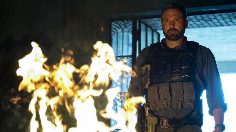 Ben Affleck în rolul lui Tom privind arderea unui morman de bani în Triple Frontier
