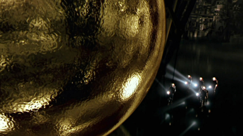 Un grup de oameni cu lanterne se apropie de sfera din Sphere