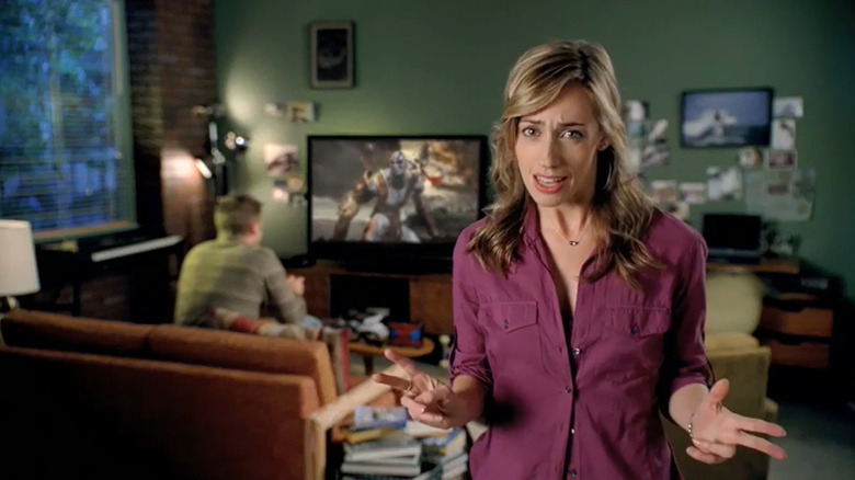 O mamă care stă în fața fiului ei, în timp ce acesta joacă God of War la televizor într-o reclamă pentru PlayStation 3.