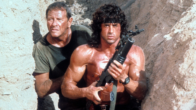 Richard Crenna în rolul colonelului Sam Trautman și Sylvester Stallone în rolul lui John Rambo, ținând un lansator de grenade, sunt așezați într-un șanț din Rambo III.