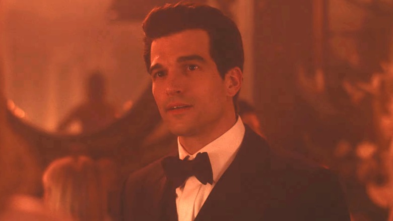 Paul Anthony Kelly în rolul lui John F Kennedy Jr stă într-o cameră iluminată cu lumină roșie în Love Story