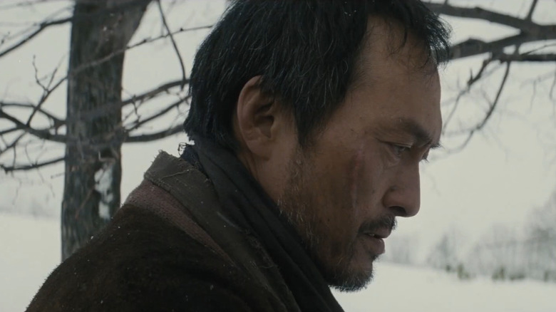 Jubei Kamata al lui Ken Watanabe este văzut în profil stând lângă copaci în Unforgiven