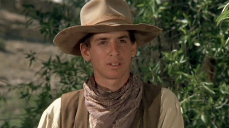 Slim Honeycutt al lui Robert Carradine se uită peste cadru în timp ce stă afară în The Cowboys