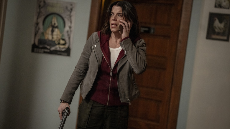 Neve Campbell în rolul Sidney Evans, arătând speriat în timp ce era la telefon și ținând un pistol în interiorul unei case în Scream 7