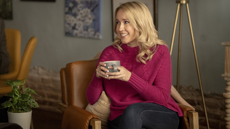 Anna Camp ca Jessica Bowden stând pe un scaun cu o ceașcă de cafea în Scream 7