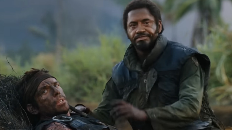 Robert Downey Jr. în rolul lui Kirk Lazarus stă deasupra Tugg Speedmanl al lui Ben Stiller în Tropic Thunder