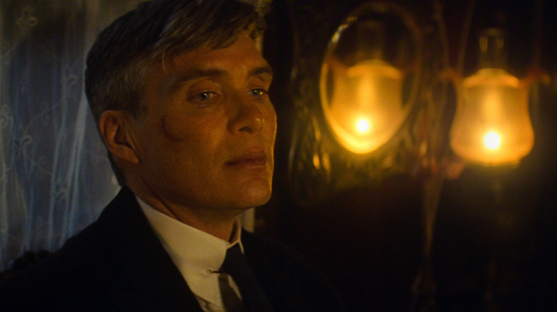 Cillian Murphy în rolul lui Tommy Shelby într-o cameră întunecată cu două lumânări în spate în Peaky Blinders: The Immortal Man