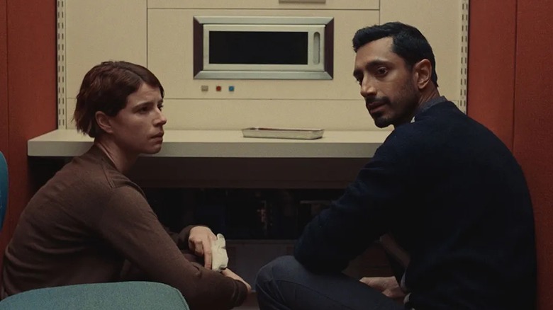 Jessie Buckley în rolul Anna și Riz Ahmed în rolul lui Amir stau lângă o mașină de testare a dragostei în Unghii