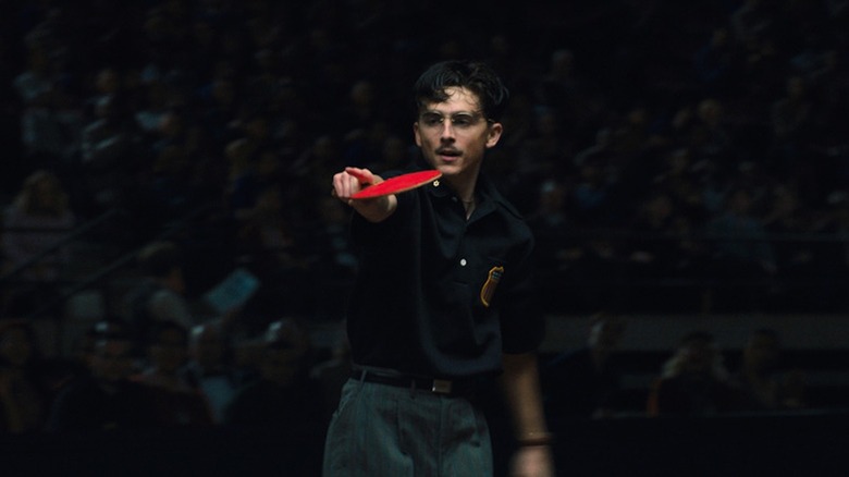 Un îngâmfat Timotheé Chalamet ține o paletă de tenis de masă în Marty Supreme