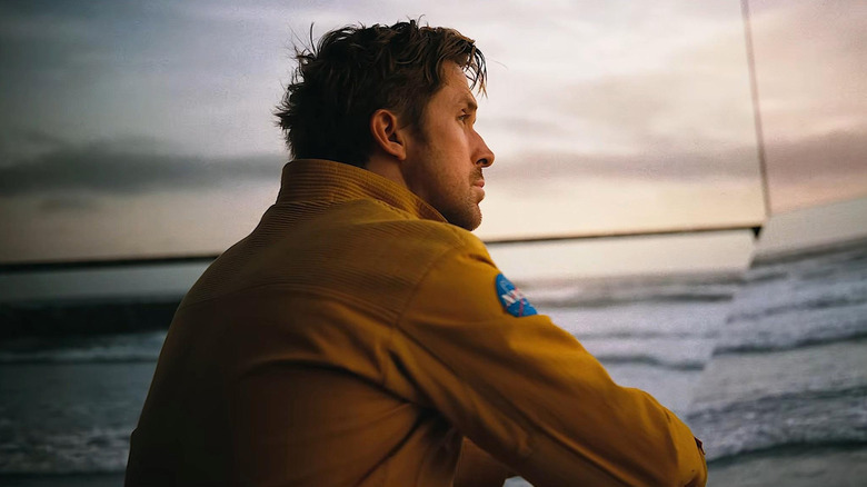 Ryan Gosling ca Ryland Grace stând într-o cameră lângă o proiecție pe ecran a unei plaje în Project Hail Mary