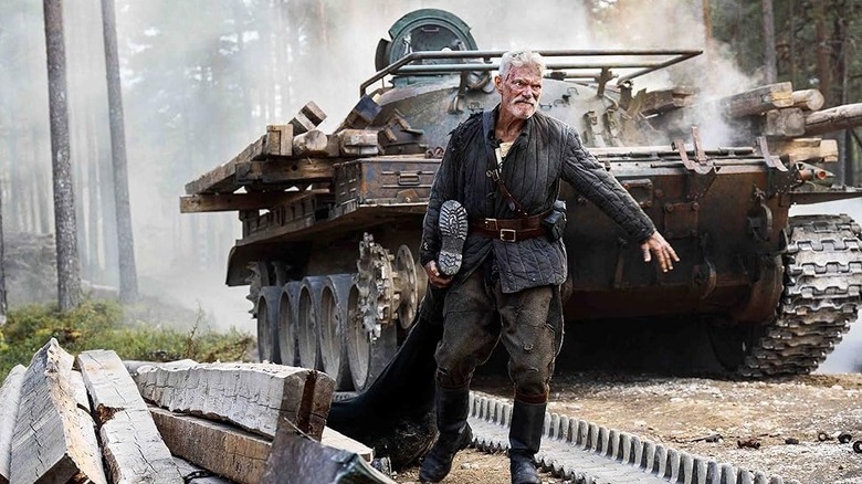Stephen Lang ca Yeagor Draganov târând un cadavru de un tanc în Sisu: Road to Revenge