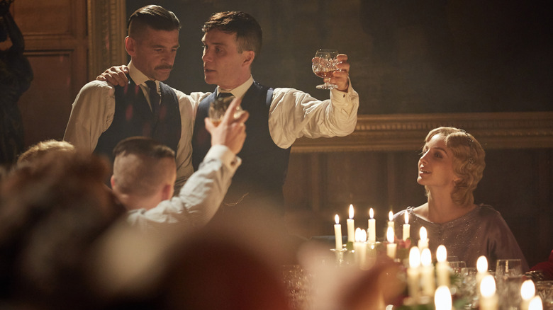Paul Anderson în rolul lui Arthur Shelby și Cillian Murphy în rolul lui Tommy Shelby împart un toast în rolul lui Annabelle Wallis, în timp ce Grace se uită în Peaky Blinders