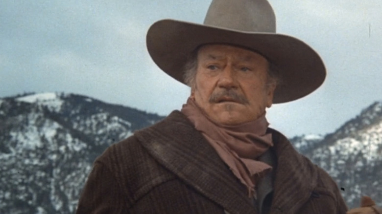 JB Books a lui John Wayne este văzută pe un fundal muntos în The Shootist