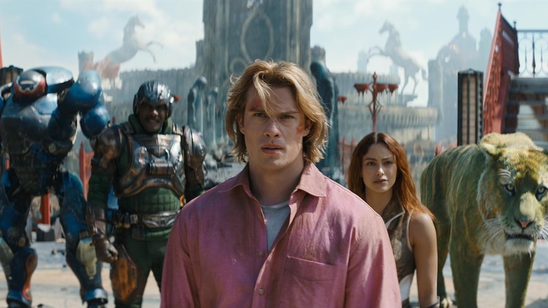 Nicholas Galitzine ca Adam/He-Man stând lângă Idris Elba ca Duncan/Man-At-Arms și Camila Mendes ca Teela în Masters of the Universe