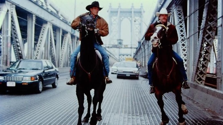 Woody Harrelson ca Pepper Lewis și Kiefer Sutherland ca Sonny Gilstrap călăresc cai pe un pod din Manhattan în The Cowboy Way