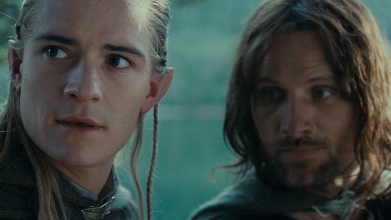 Orlando Bloom în rolul lui Legolas stând lângă Viggo Mortensen în rolul lui Aragorn lângă malul unui râu în Stăpânul Inelelor: Frăția Inelului