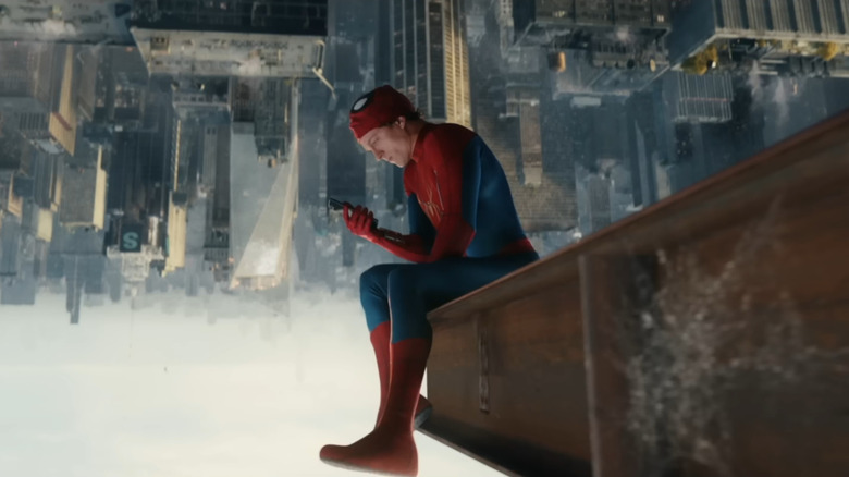 Tom Holland în rolul lui Peter Parker care stă cu capul în jos pe o grilă de oțel cu vedere la New York și se uită la telefonul său în Spider-Man: Brand New Day