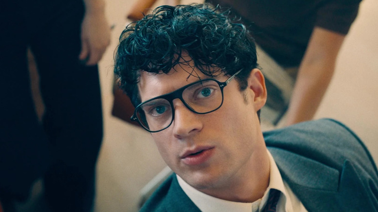 David Corenswet în rolul lui Clark Kent privind la televizor de pe biroul lui în Superman