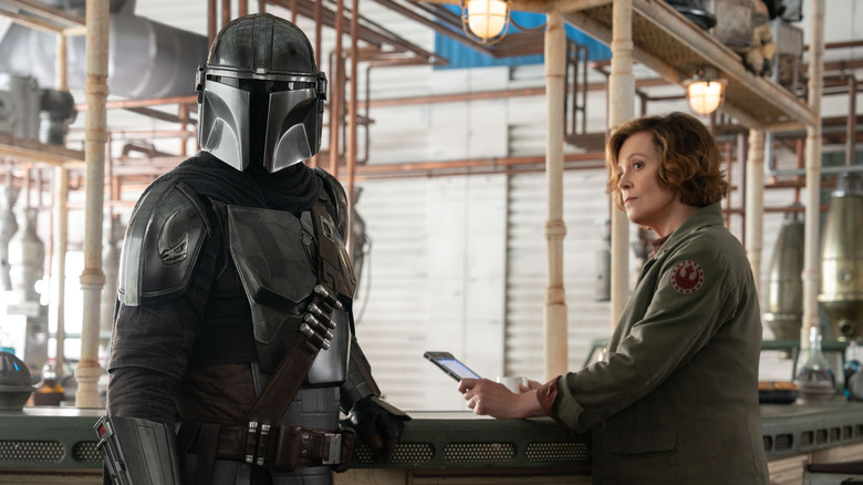 Pedro Pascal ca Mando și Sigourney Weaver ca colonelul Ward stând la un bar în The Mandalorian și Grogu