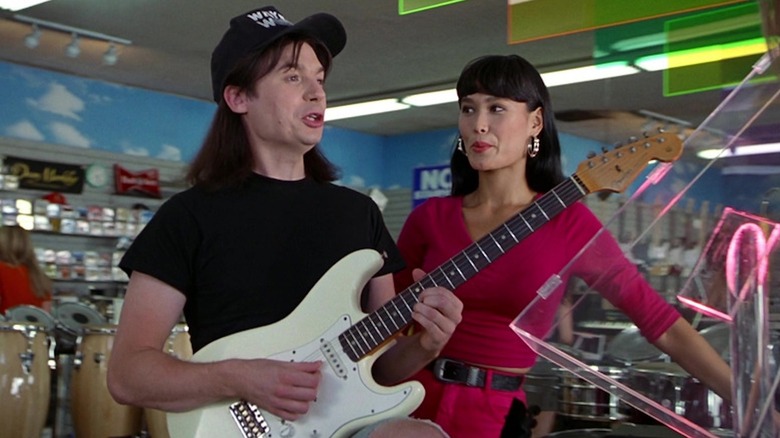 Mike Myers în rolul Wayne Campbell mânuiește un Fender, în timp ce Tia Carrere în rolul Cassandra Wong se uită în Wayne's World