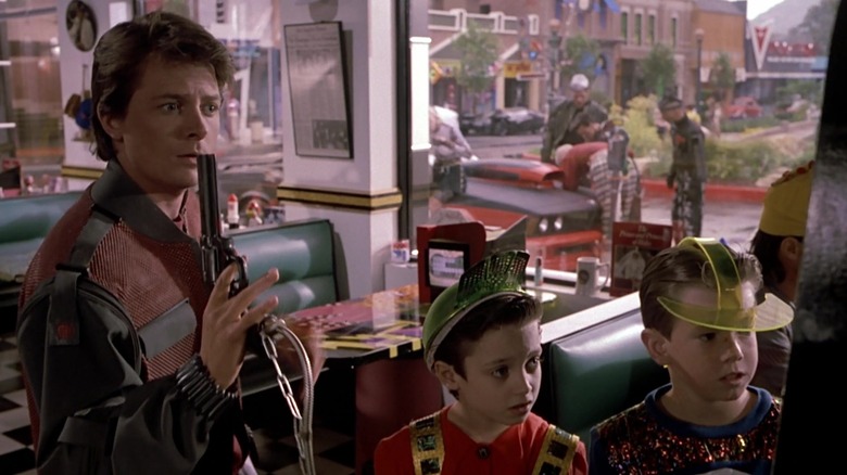 Marty McFly folosește un pistol arcade în timp ce doi băieți se uită în Back to the Future Part II