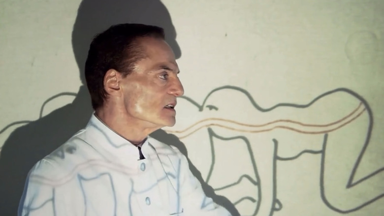 Josef Heiter de la Dieter Laser stă în fața unei diagrame din Prima secvență The Human Centipede