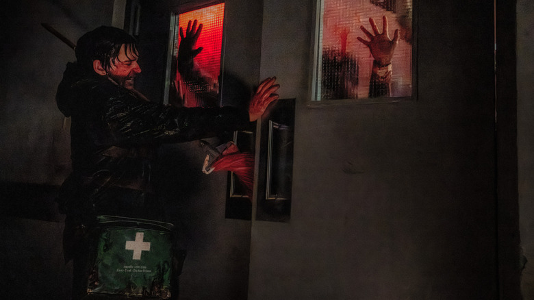 Austin Abrams în rolul lui Bryan care încearcă să închidă o ușă în timp ce este infectat a bătut ferestrele cu mâinile în Resident Evil