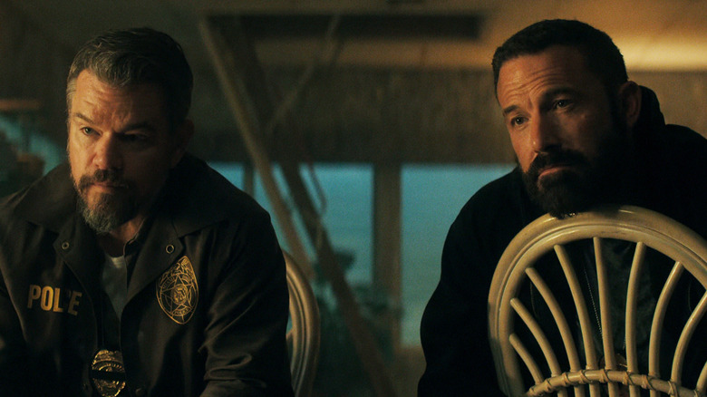 Locotenentul lui Matt Damon, Dane Dumars, și sergentul detectiv al lui Ben Affleck, JD Byrne, stau unul lângă altul pe scaune privind pe cineva în afara ecranului în The Rip