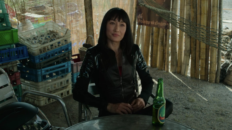 Anna Dutton de la Maggie Q stă la o masă cu o bere în The Protégé