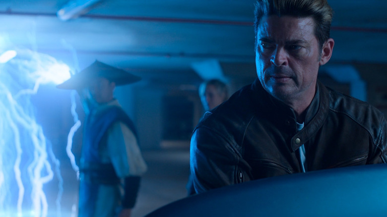 Karl Urban în rolul lui Johnny Cage privind în urmă la Tadanobu Asano în rolul lui Raiden și la Jessica McNamee în rolul Sonya în Mortal Kombat II
