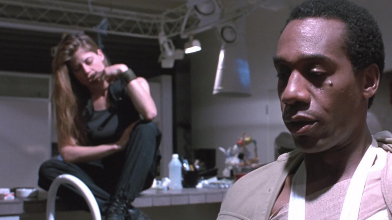 Sarah Connor din Linda Hamilton stă pe un dulap de bucătărie, în timp ce Miles Dyson din Joe Morton arată abătut în prim-plan în Terminator 2 Judgment Day