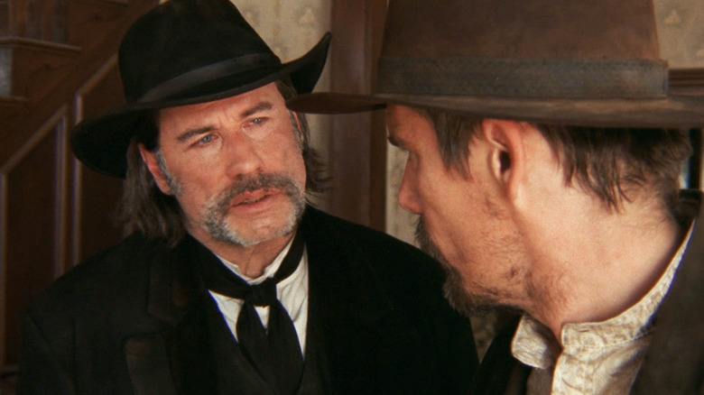 Clyde Martin al lui John Travolta îl privește pe Paul al lui Ethan Hawke în timp ce stau într-o casă din In a Valley of Violence