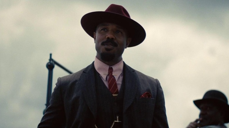 Michael B. Jordan ca Smoke stând lângă mașină în Sinners