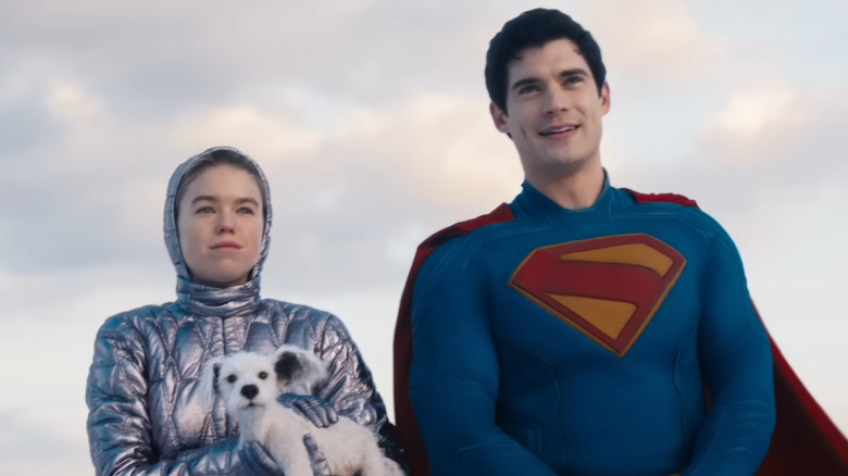 Milly Alcock ca Kara Zor-El ținând Krypto după ce a sosit pe Pământ stând lângă David Corenswet ca Superman în Supergirl