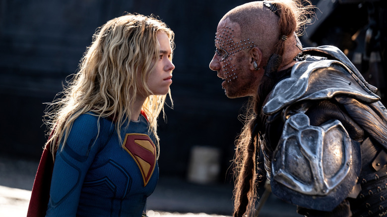 Milly Alcock în rolul Supergirl, purtând ținuta ei de super-erou și stând față în față cu Matthias Schoenaerts în rolul lui Krem în Supergirl