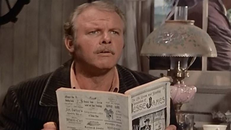 Alan Hale Jr. în timp ce Cole Younger citește o foaie de scandal despre isprăvile lui Jesse James în The True Story of Jesse James
