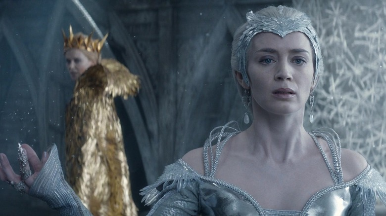 Emily Blunt în rolul Freya care arată îngrijorată în rolul Charlize Theron, în timp ce Ravenna o înconjoară în The Huntsman: Winter's War