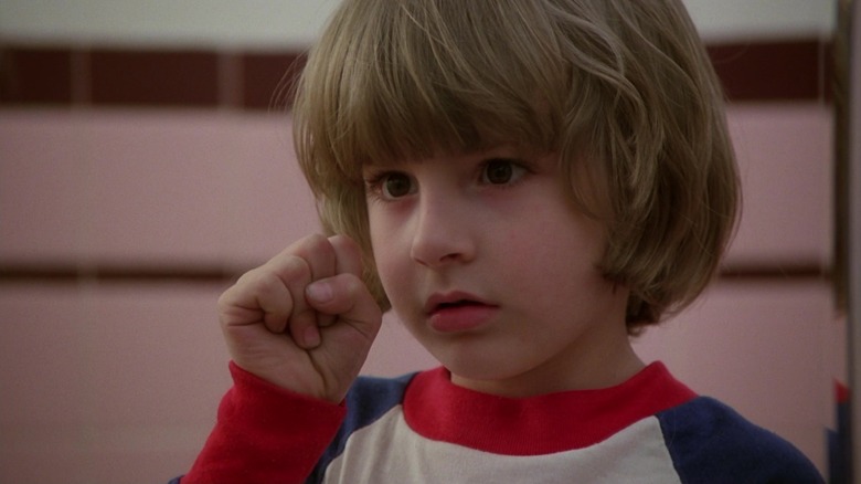 Danny Torrance, de la Danny Lloyd, ridică pumnul în timp ce se uită într-o oglindă în The Shining