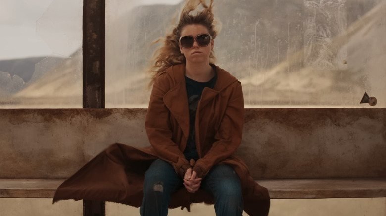 Milly Alcock în rolul lui Kara Zor-El stând la stația de autobuz din Supergirl