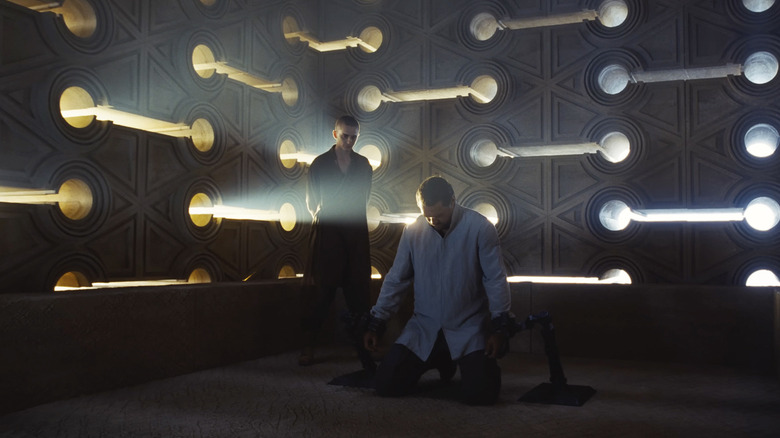 Paul Atreides stă în colțul unei camere cu aspect futurist, planând peste Duncan Idaho, care este în genunchi, în Dune: Capitolul trei
