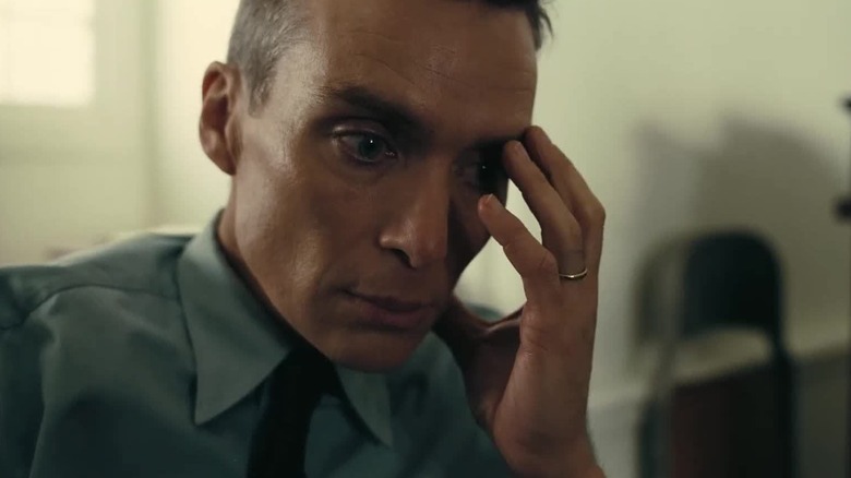 Cillian Murphy ca J. Robert Oppenheimer ținându-și fața în Oppenheimer