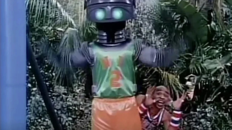Un jucător de la Harlem Globetrotters stă în spatele unui robot pe un teren de baschet în Harlem Globetrotters de pe Insula lui Gilligan