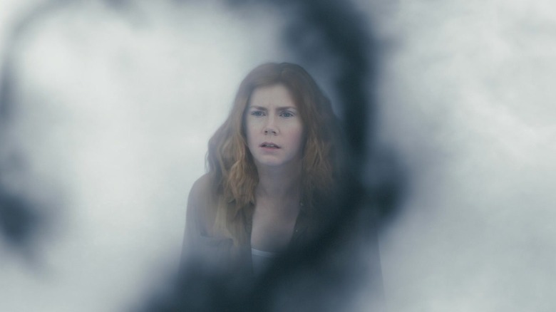 Louise într-un loc plin de fum privind un glif extraterestru din Arrival
