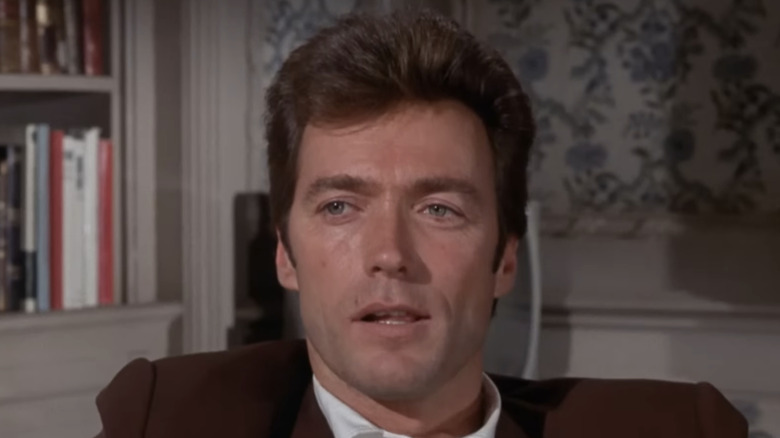 Walter Coogan din Clint Eastwood zâmbește și se uită în dreapta lui în timp ce se așează în Coogans' Bluff