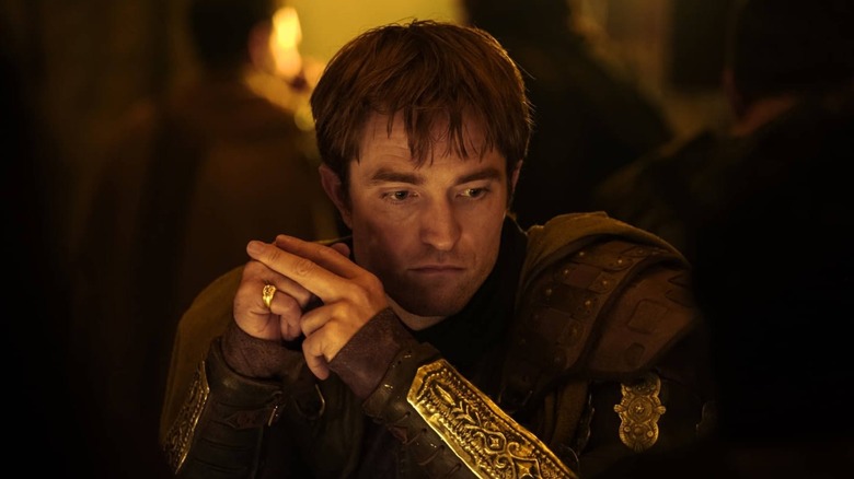 Robert Pattinson în rolul lui Antinous așezat la o masă în The Odyssey