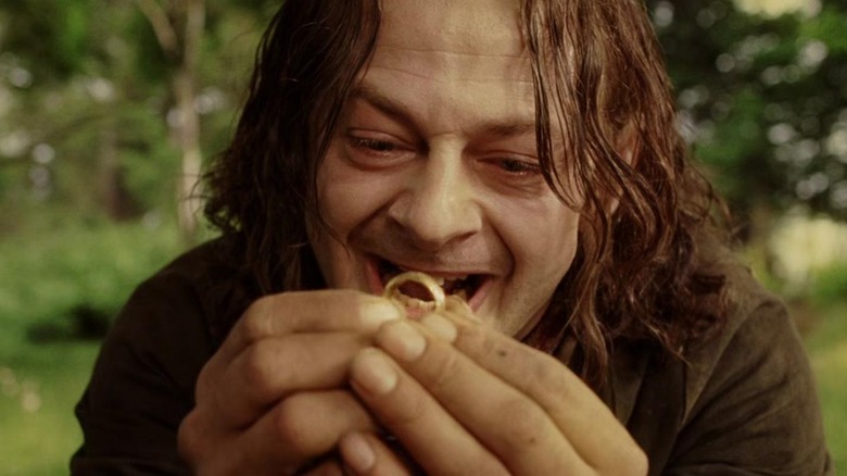 Andy Serkis în rolul lui Sméagol ținând în sus un inel de aur și zâmbind într-o zonă împădurită în Stăpânul Inelelor: Întoarcerea Regelui