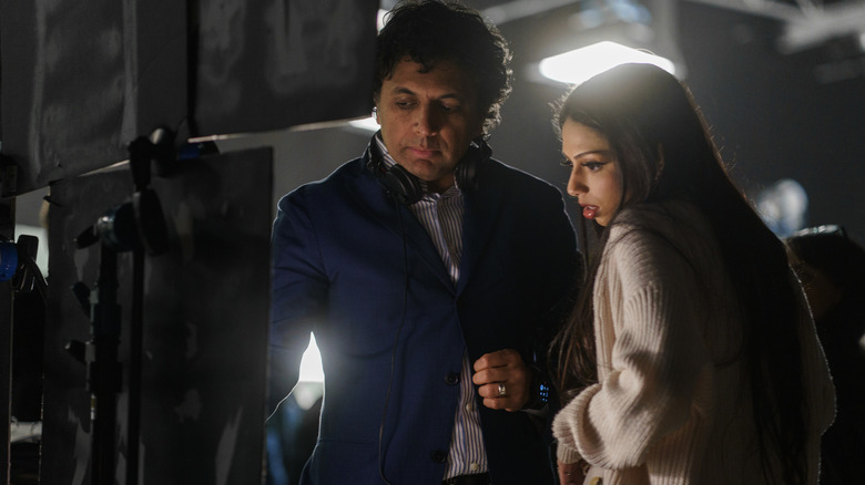 Regizorul M. Night Shyamalan stând lângă un monitor cu fiica sa Saleka Night Shyamalan în rolul Lady Raven pe platoul de filmare al filmului Trap