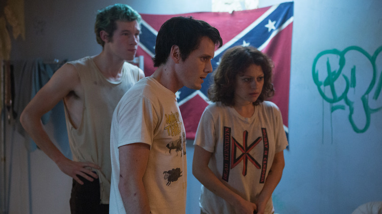 Callum Turner în rolul Tigerului, Anton Yelchin în rolul lui Pat și Alia Shawkat în rolul lui Sam privind o ușă din Green Room