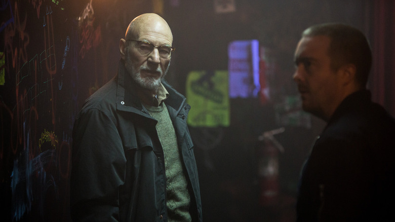 Patrick Stewart în rolul lui Darcy și Macon Blair în rolul lui Gabe stând pe un hol din Green Room